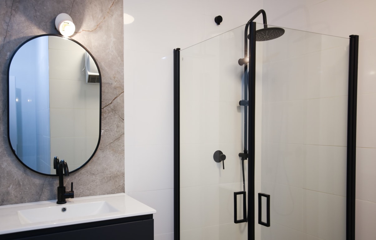 עיצוב מקלחון פינתי עם דלתות כנפיים ומסגרת שחורה