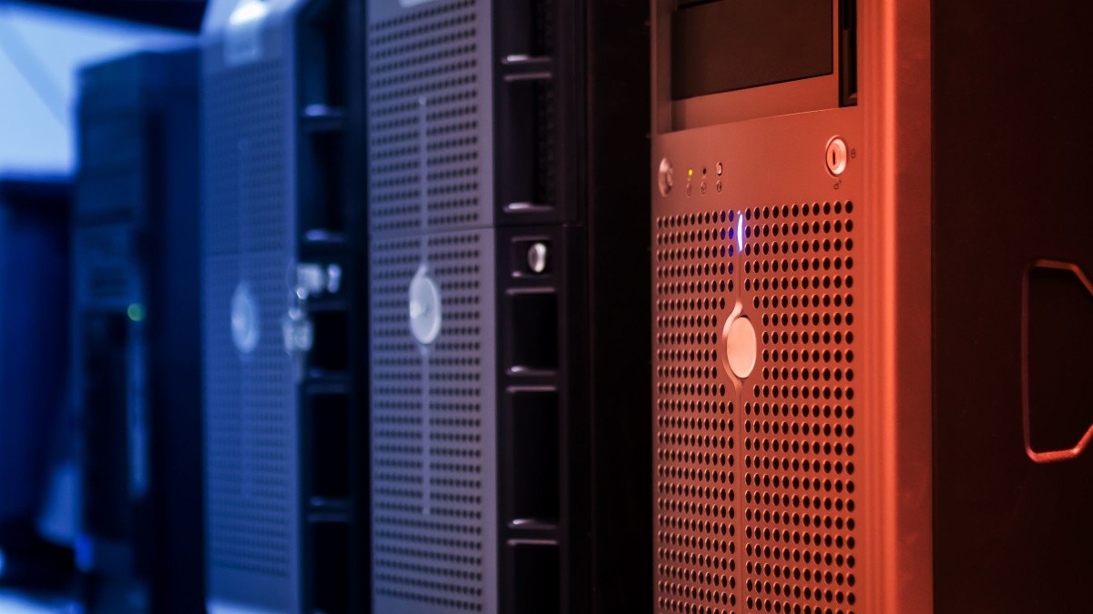 A row of rack-mounted server towers in a data centre, lit in blue and red.