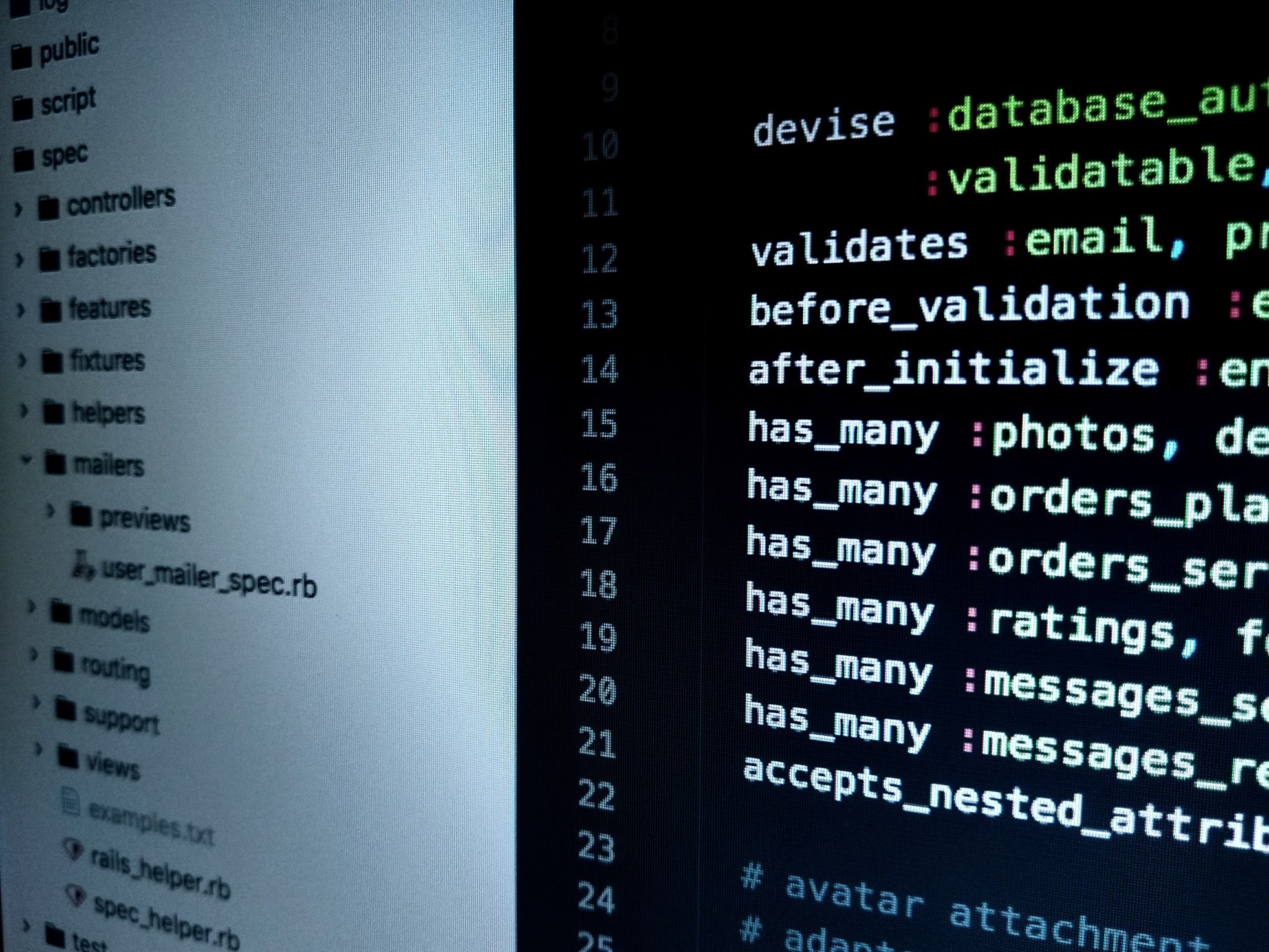 Ruby on Rails source code and a project file tree displayed on a monitor.