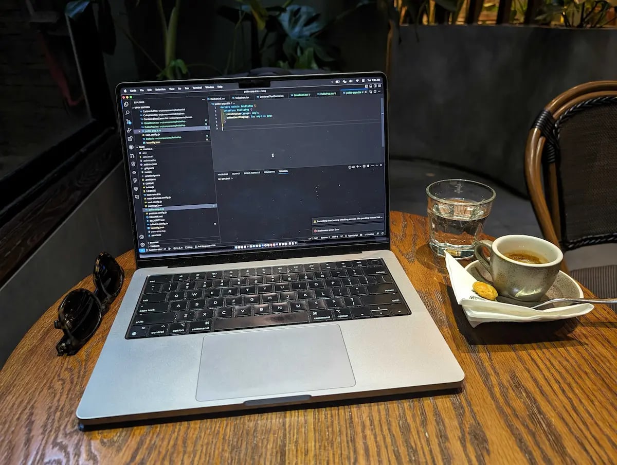 My laptop on a table next to an espresso and a glass of water, at a cafe in Hanoi