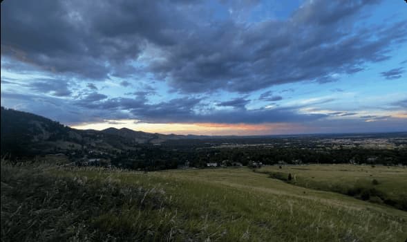 Photo of a sunset over a hiking trail, with mountains in the background