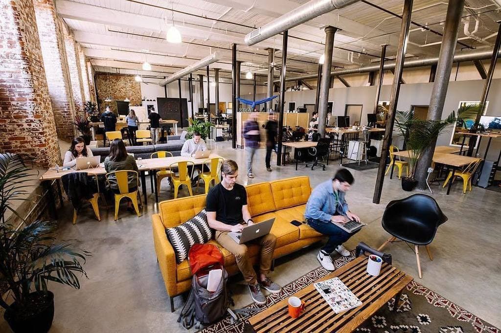 Photo of a coworking space, with people working at desks in an open office space