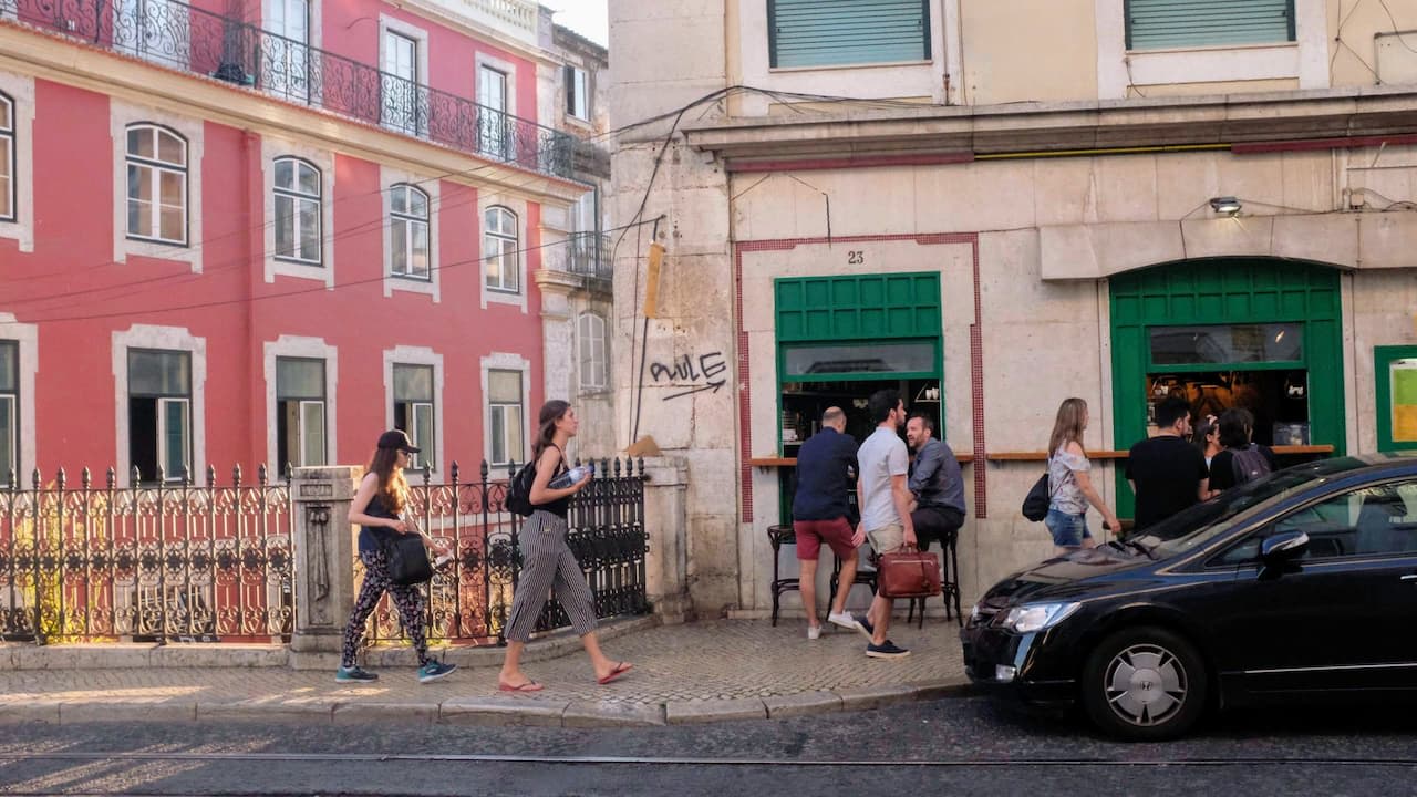 A photo of a city street in Lisbon, with people walking together and talking