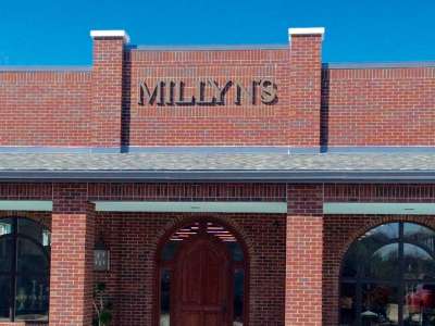 Stately brick storefront with large arched double doorway and gold signage reading Millyn's.