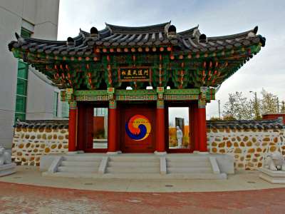 Strikingly large gate built in the South Korean Hongsalmun style, painted with bright colors and decorated with symbols. 