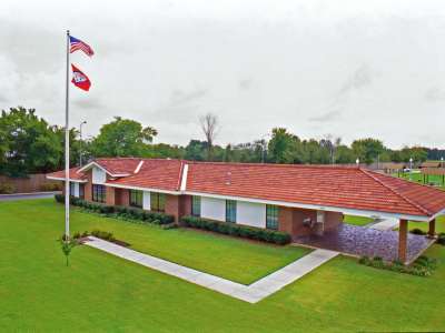 Exterior, arial view of a long, one story building with a red shingle roof.