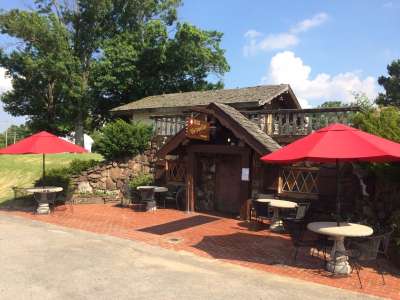 Store front of Wiederkehr Winery with brick paved patio and concrete benches with bright red umbrellas.