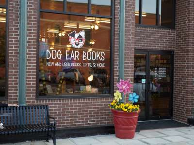 Store front with flower pot and window sign reading, Dog Ear Books.