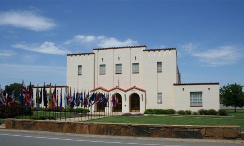 A white building with flags lining the path to the entrance.