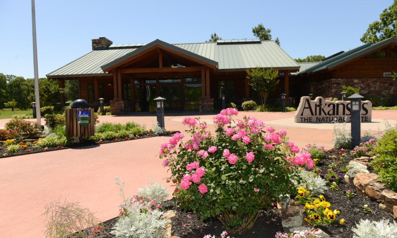 A bush with bright pink flowers in front of the entrance of the building.