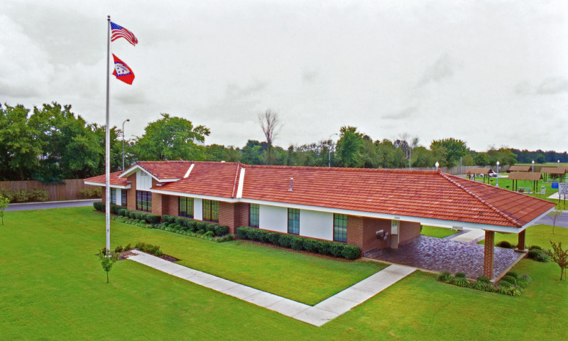 Exterior, arial view of a long, one story building with a red shingle roof.