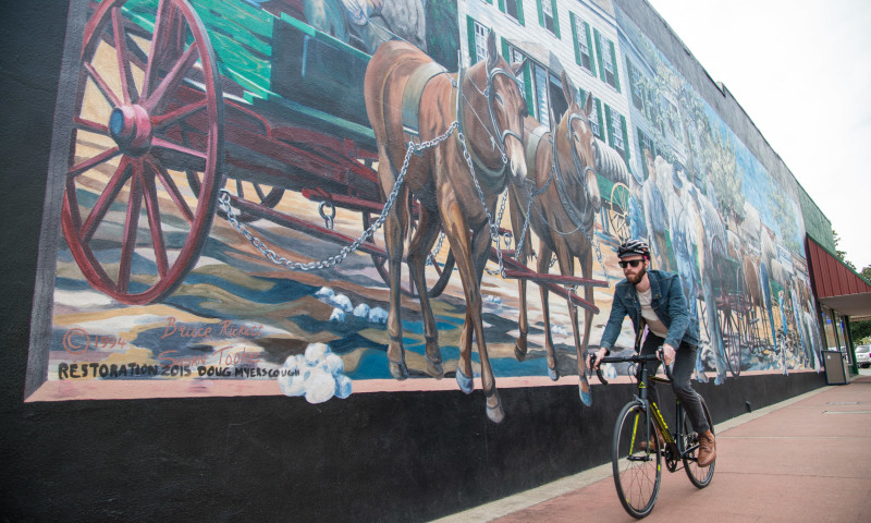 Cycling past a mural in Magnolia on the Tour of Columbia County