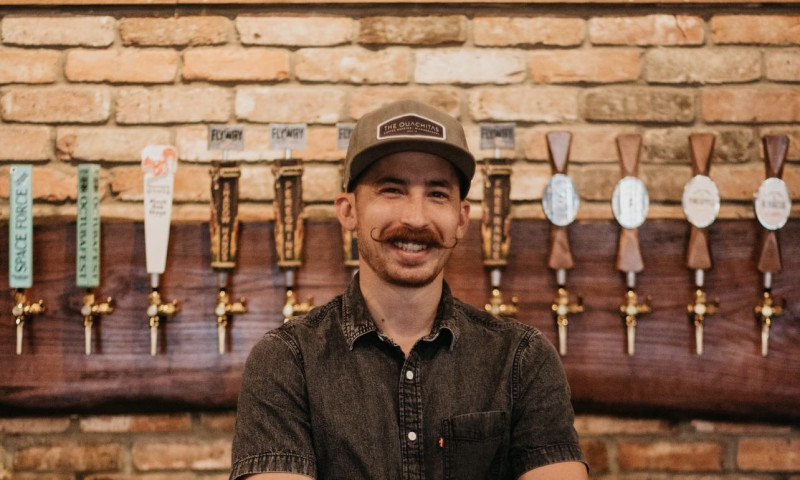 Owner Derek Campbell stands in front of the taproom wall.