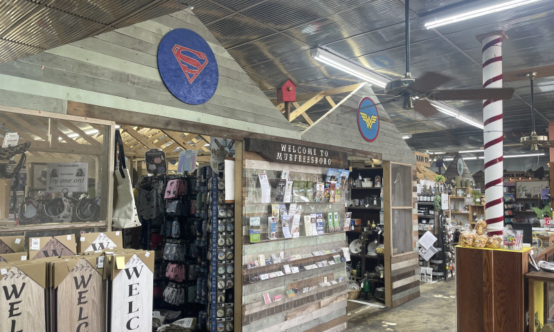 Inside of large flea market with shopping displays and welcome signs.