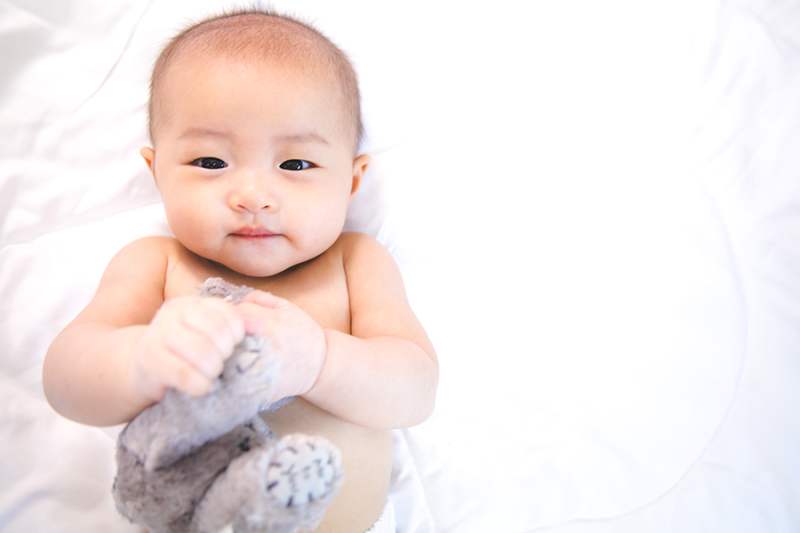 Baby lying on bed looking at camera