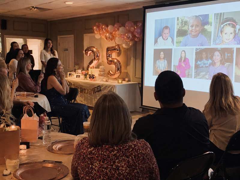 Friends watch a birthday slideshow during a 25th birthday party