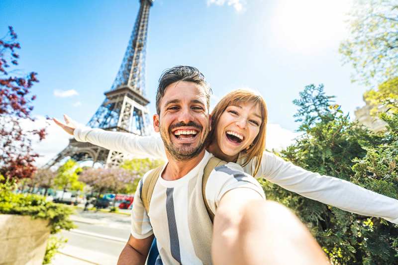 Happy couple of tourists taking selfie picture at the Eiffel Tower
