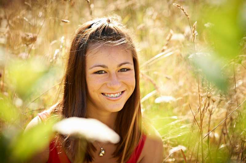 High school senior girl smiling in tall grass