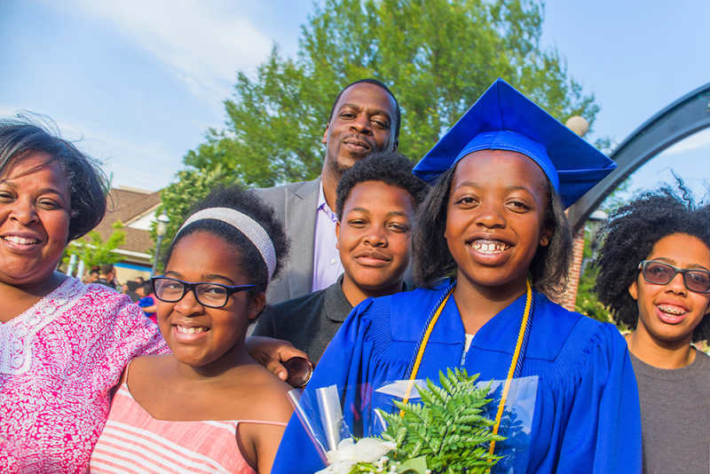 Portrait of teenage girl with family on her high school graduation day