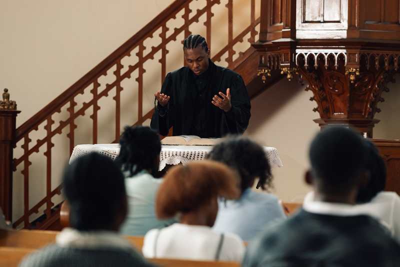 Young priest giving sermon at a memorial service repass