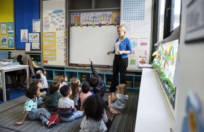 Kindergarten students sitting on the floor listening to teacher Kindergarten students sitting on the floor listening to teacher
