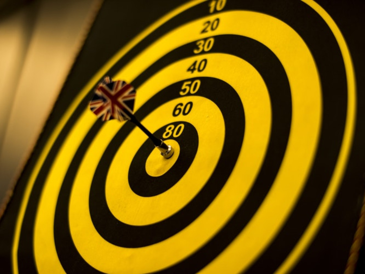 Photo of a darts board with a dart puncturing the bullseye