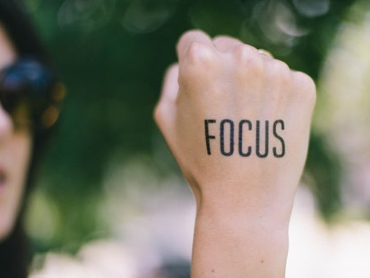 Photo of a tattoo of the word focus on the back of a woman's hand that is closed in a fist