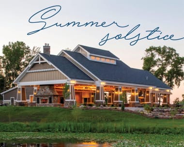 Elegant house with a large porch, set in a lush garden by a pond at dusk. Warm lights create a cozy atmosphere. "Summer Solstice" text above.