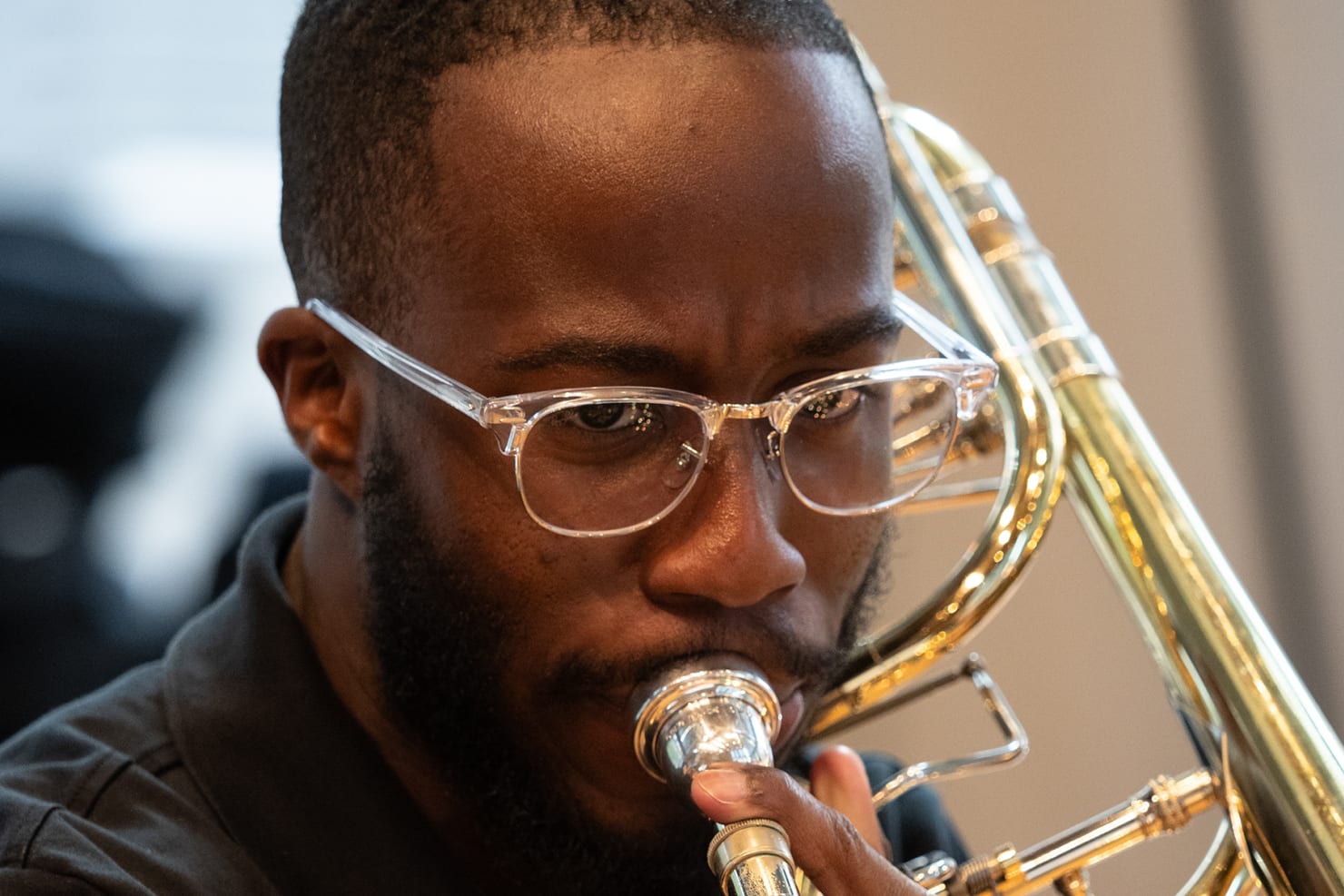 Lovrick Gary III seated and playing trombone in Orchestra Hall's Target Atrium