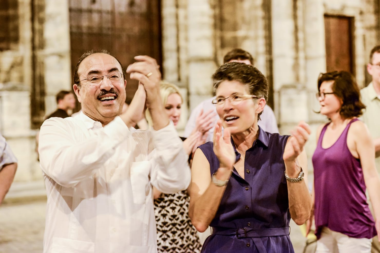 A group includes Minnesota Orchestra Principal Trumpet Manny Laureano and violinist Deborah Serafini, clapping during the 2015 Cuba tour.