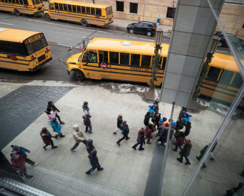 Groups of students walking into Orchestra Hall with buses along the street