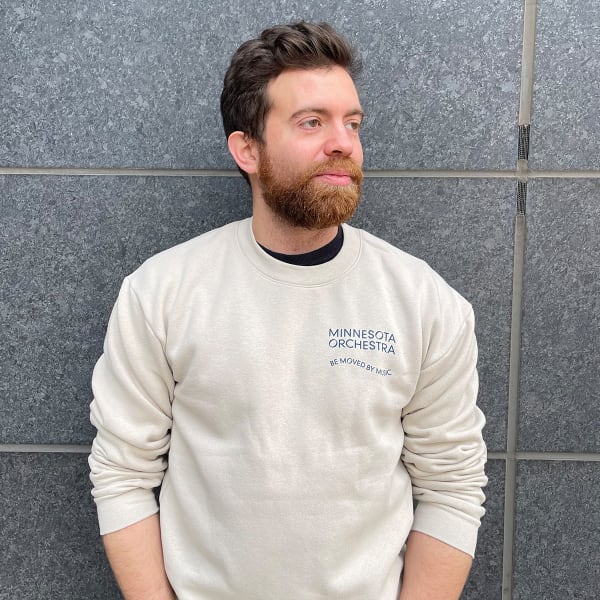 Mn Orchestra musician Erich Rieppel wearing a Bone-colored sweatshirt with the Minnesota Orchestra logo