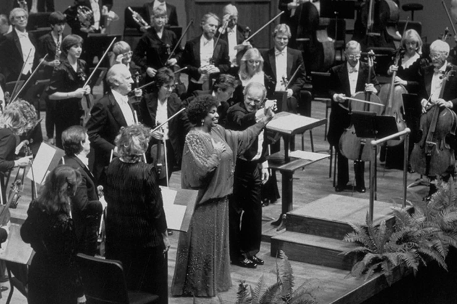 Edo de Waart holding up hands with Leontyne Price and orchestra standing behind them