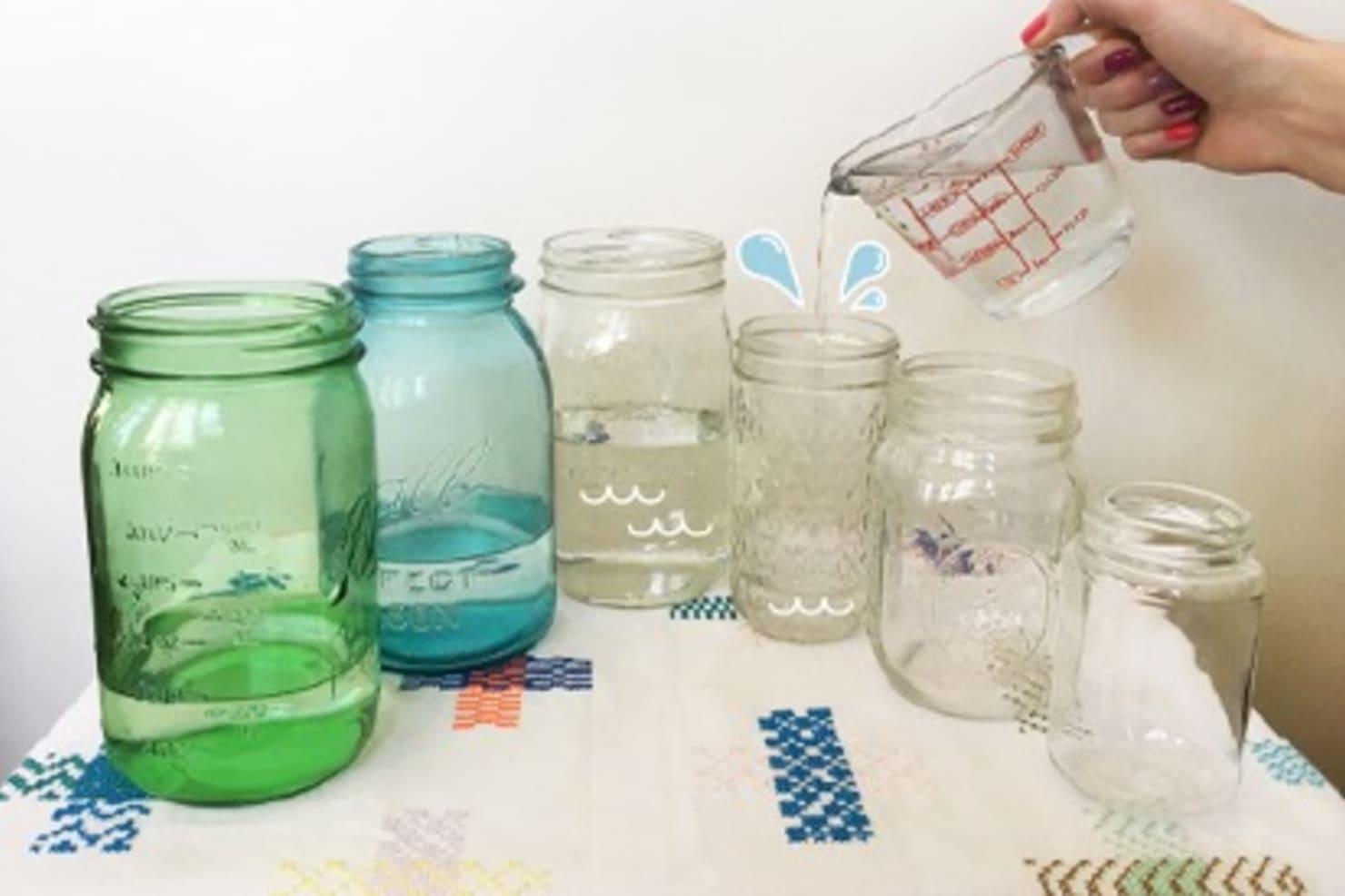 Colorful jars with water being poured into them