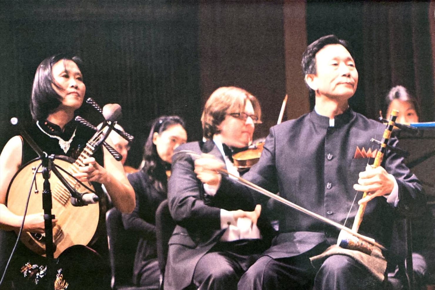 Mei Hu, left, and Zhengang Xie, right, perform the yue qin and jing hu in front of an orchestra