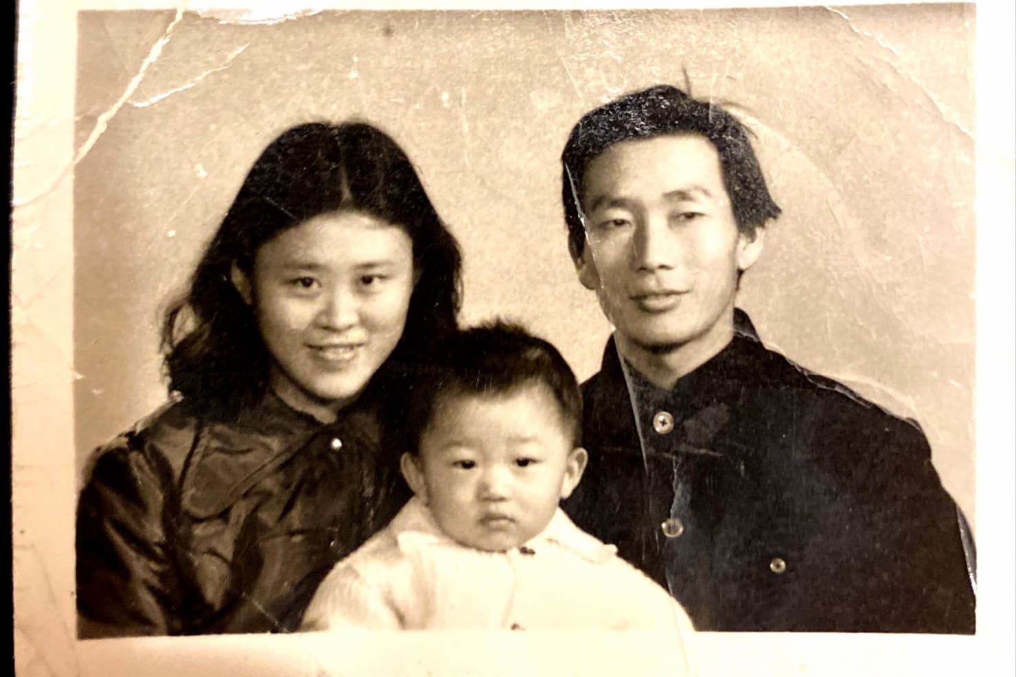 Mei Hu, left, Zhengang Xie, right, and young Fei Xie pose for a black and white family photo 