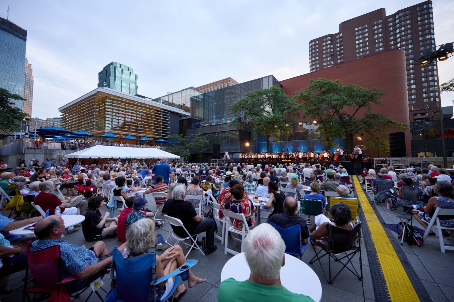 An outdoor performance in a large downtown park, Peavey Plaza, with the Orchestra playing onstage.