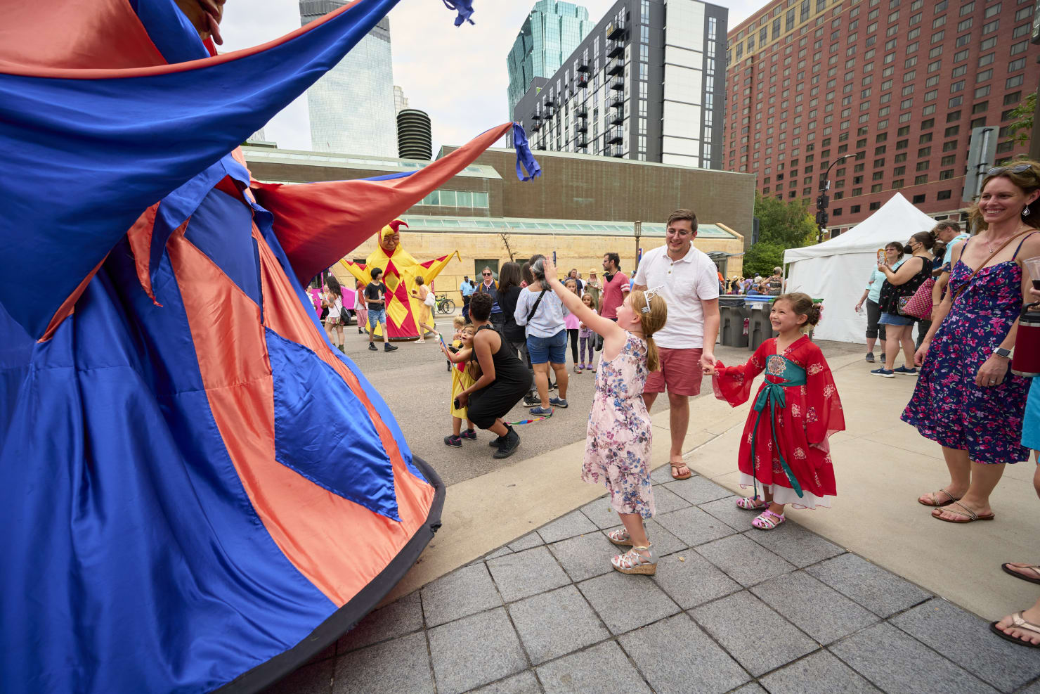 Children interacting with large puppets outdoors