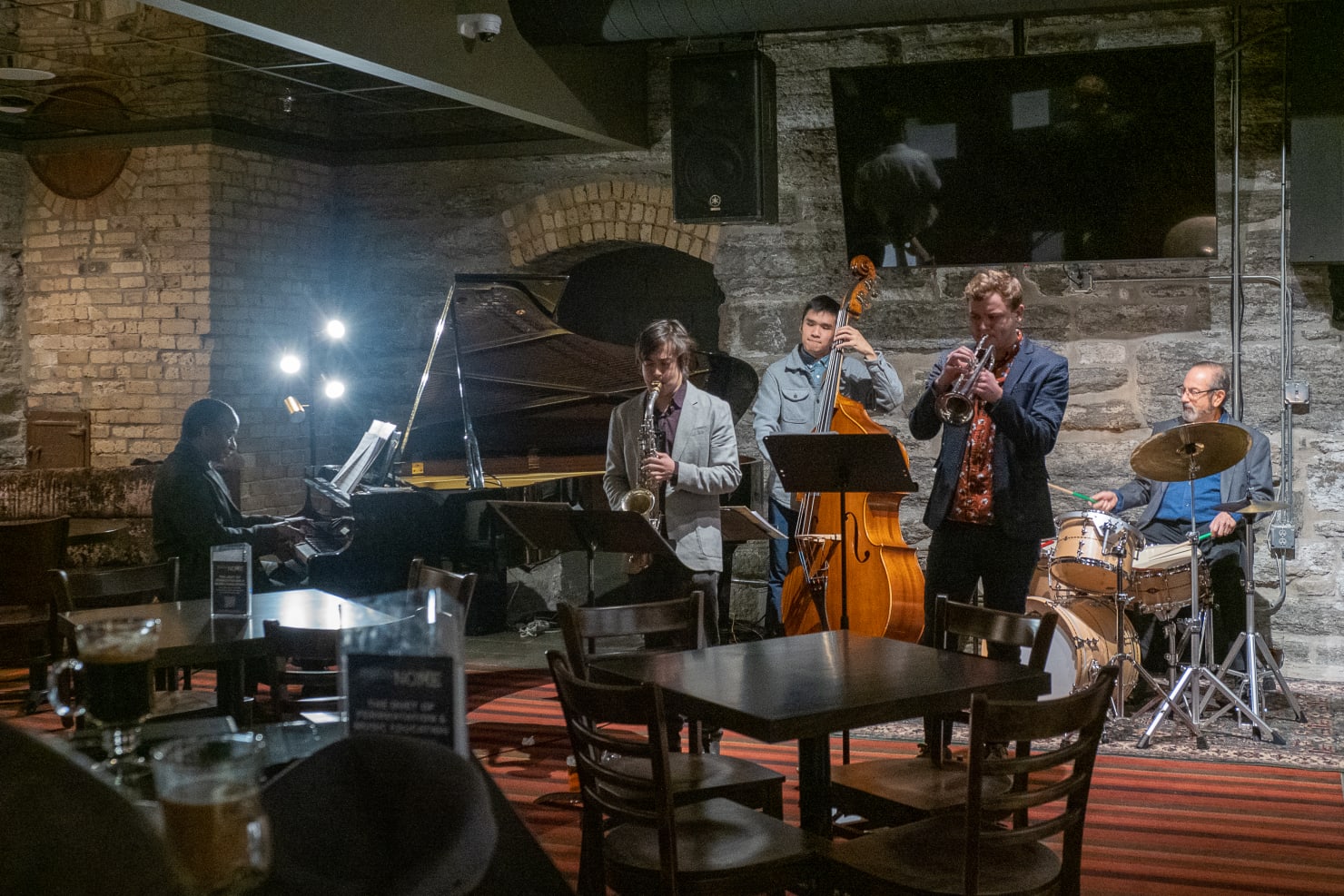 Five musicians (a pianist, saxophone player, bass player, trumpet player and Peter Kogan on drum set, performing at MetroNOME Brewery.