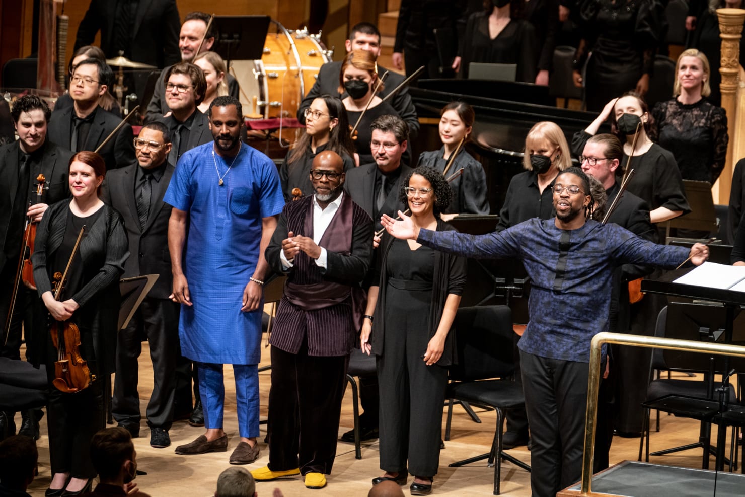 The main artistic leaders behind brea(d)th take a bow on the stage; members of the Orchestra stand behind them.