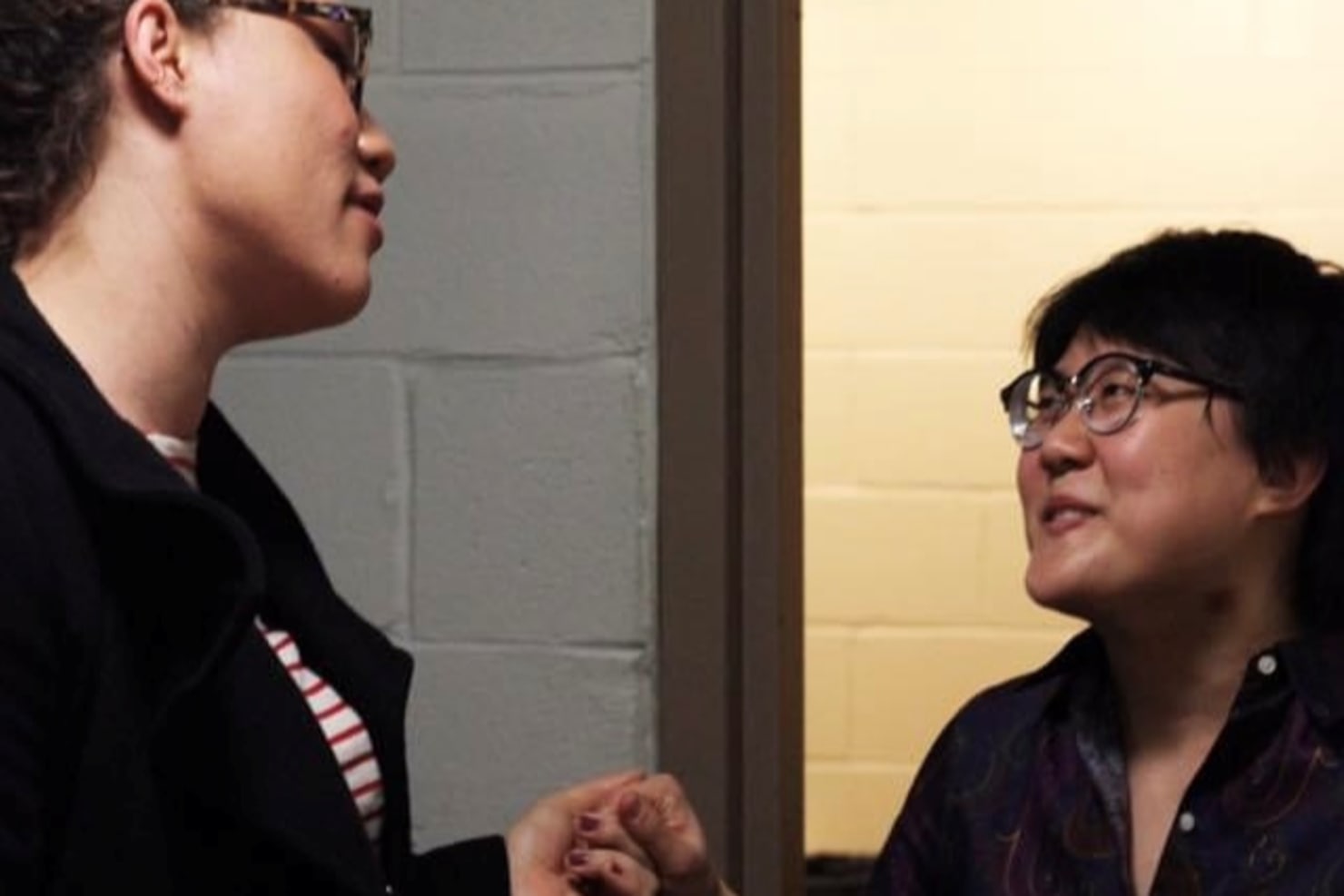 A close-up image of Marlea Simpson and Jude Simpson smiling one another, holding hands backstage.