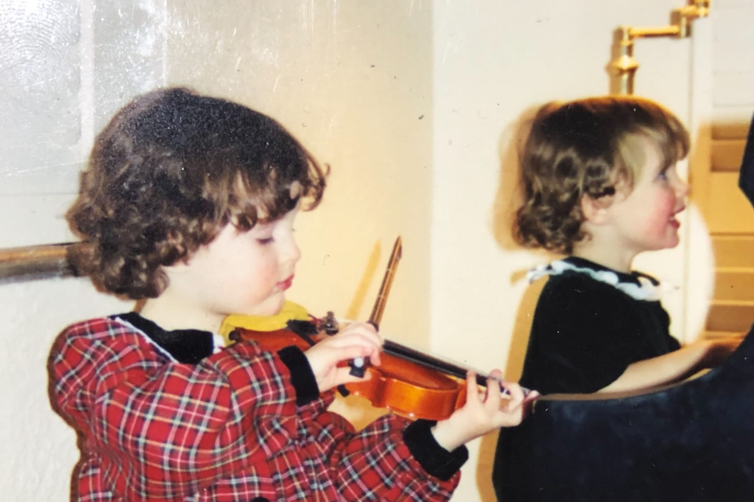 Emily and Sarah as little girls, playing the violin and piano in their living room.