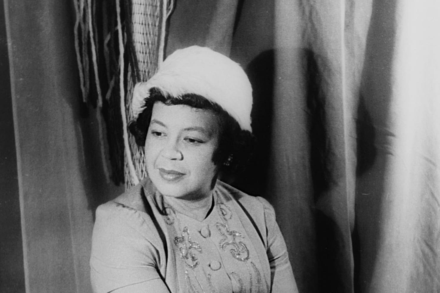 A black and white portrait of Margaret Bonds, a black woman, posing for the camera her hands resting on her crossed knees.