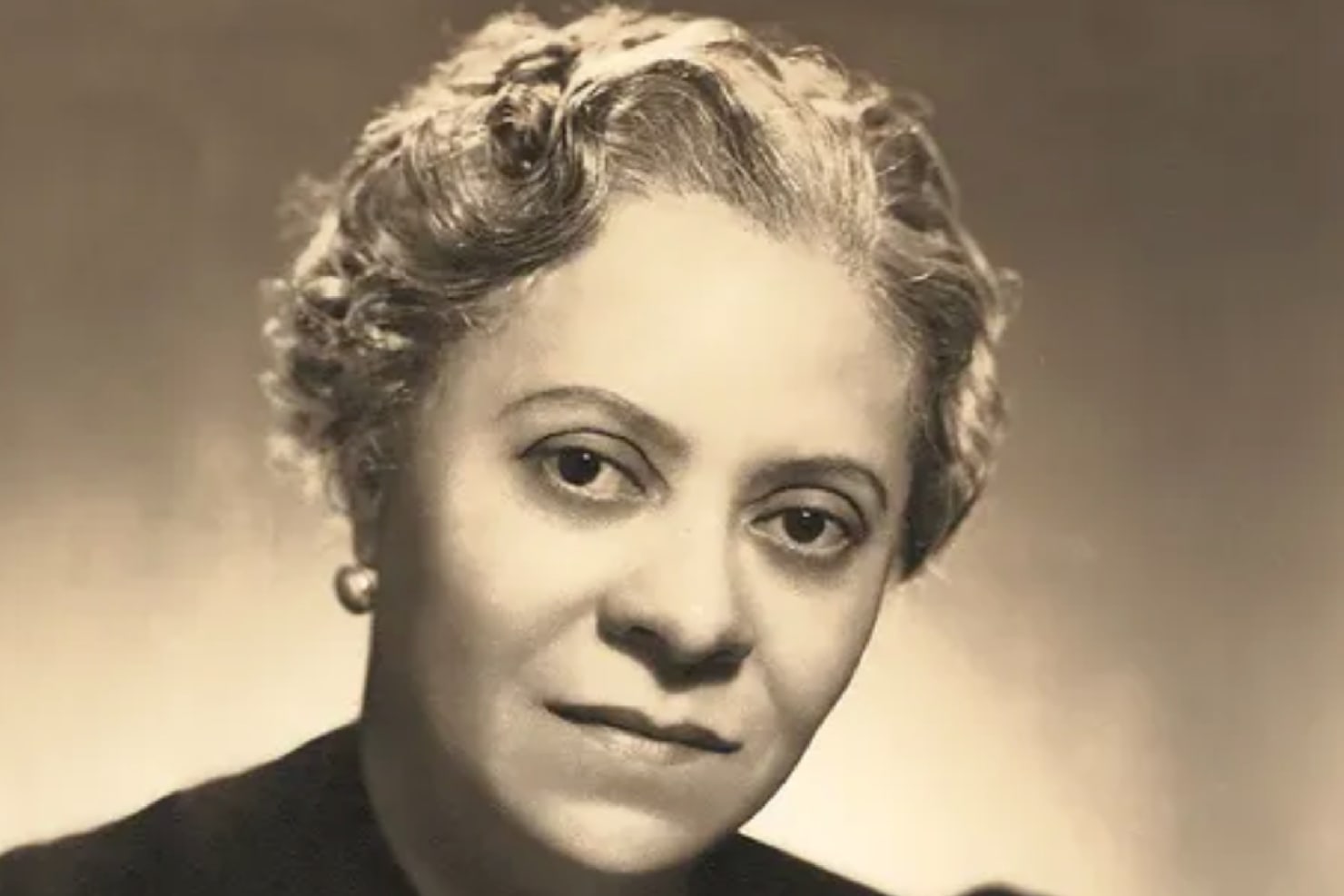 A black and white portrait of Florence Price, a black woman, looking directly at the camera.