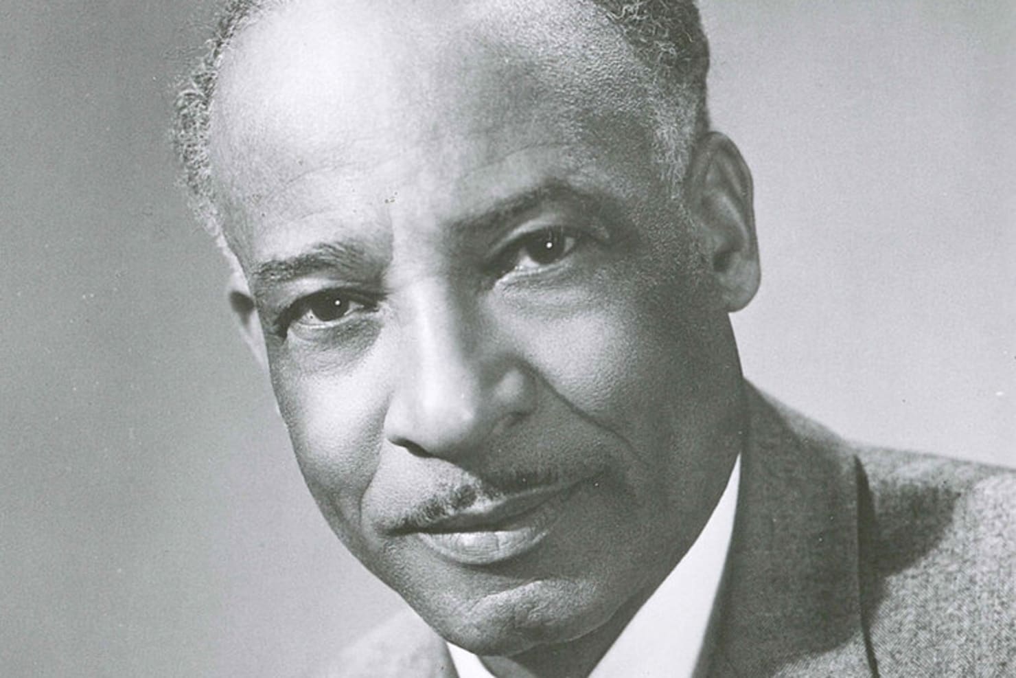 A black and white photo of William Dawson, a black man wearing a suit against a plain background, looking directly at the camera.