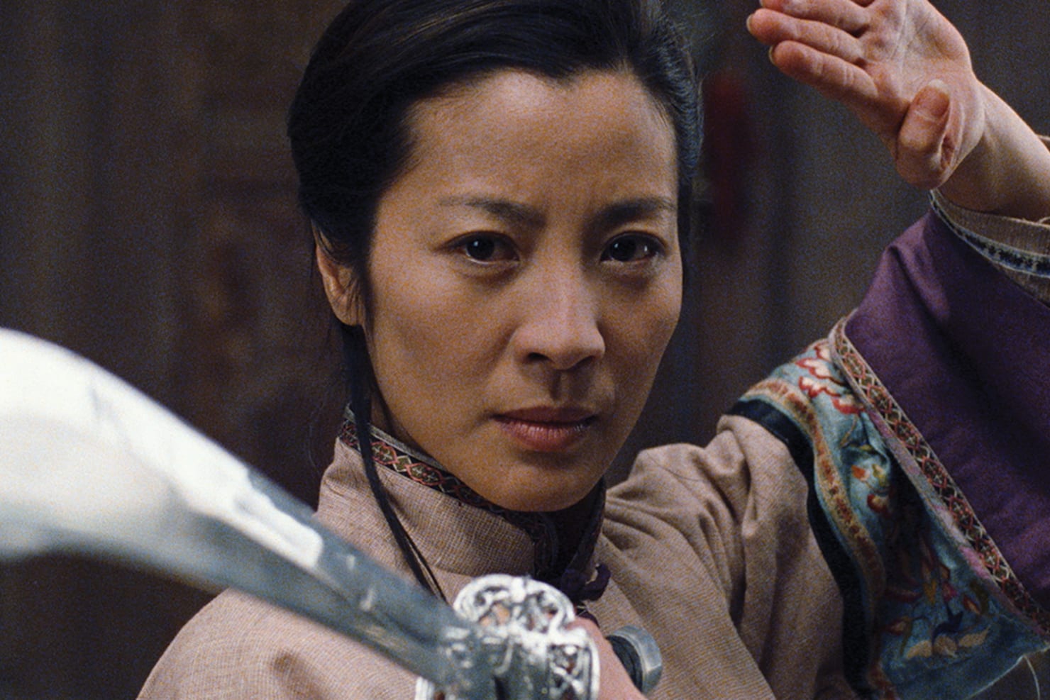 A movie still of Michelle Yeoh, pointing a sword.