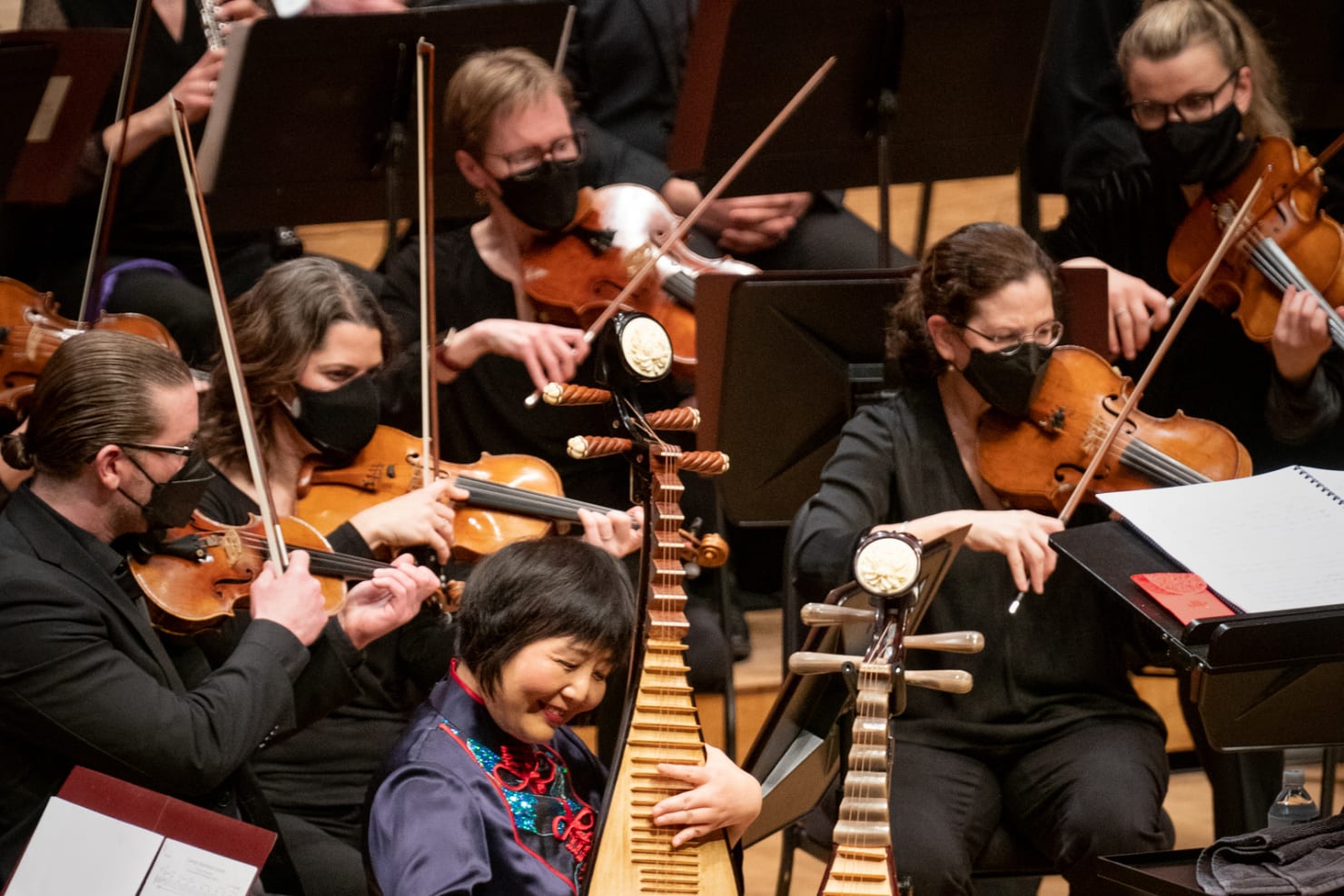 An image of the Orchestra on stage at Orchestra Hall, with pipa player Gao Hong at the front.