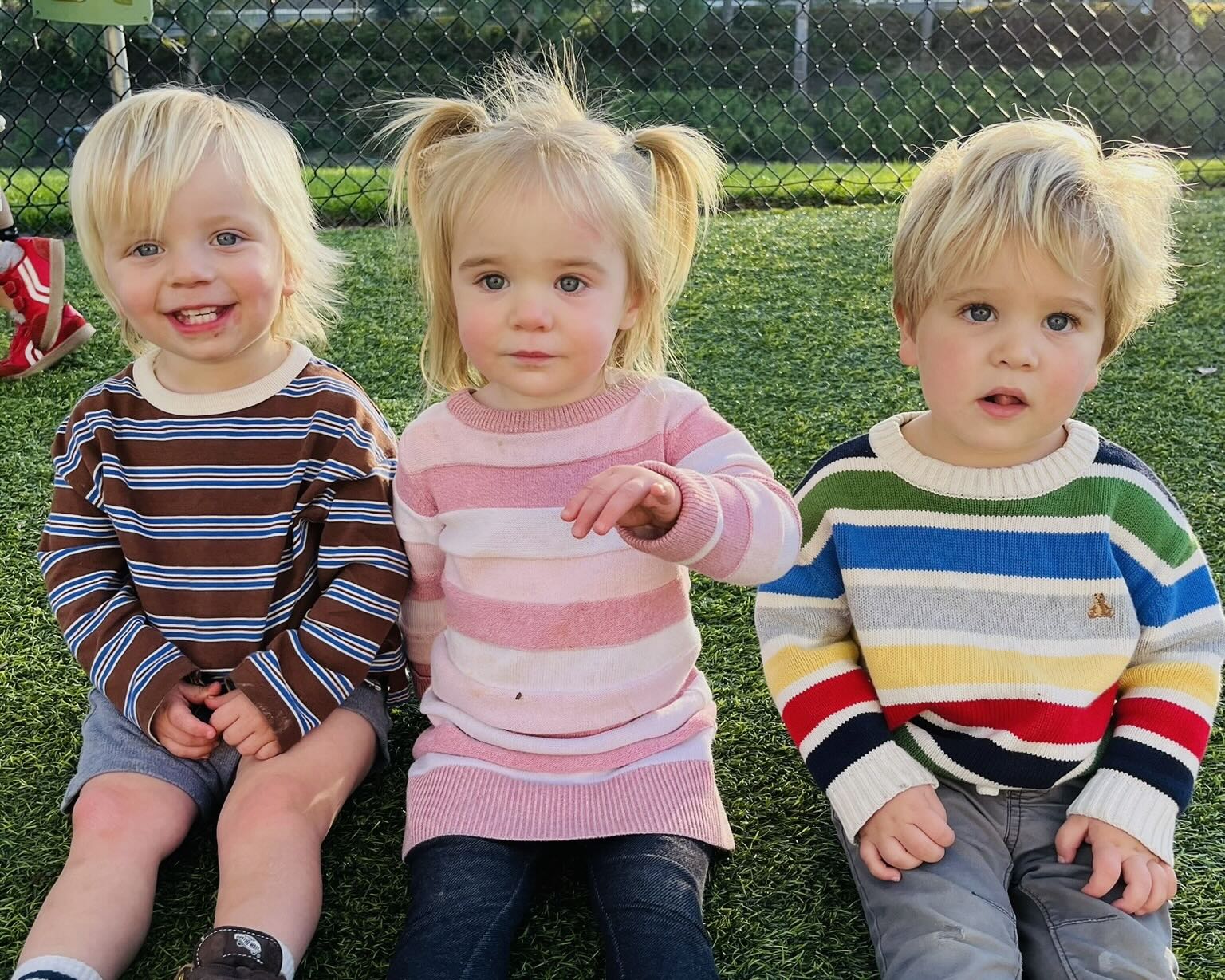 Preschool boy painting on large paper with a paintbrush, smiling.