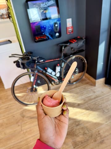 Me holding a gelato cup with my bicycle in the background