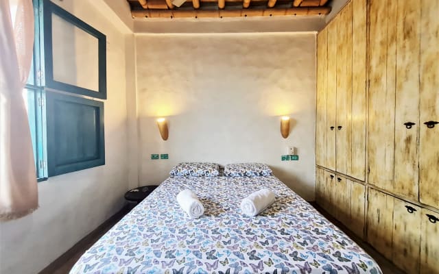 Zweibettzimmer mit Deckenventilator und Seitenfenster.